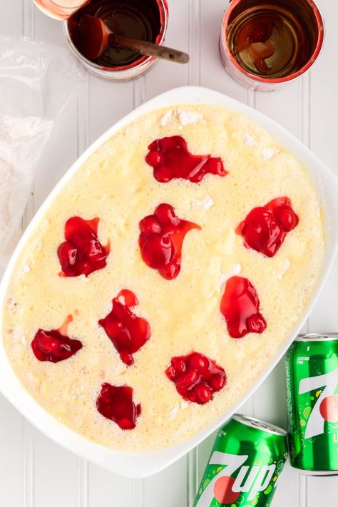 Cherry pie filling being dolloped over the cake mix.