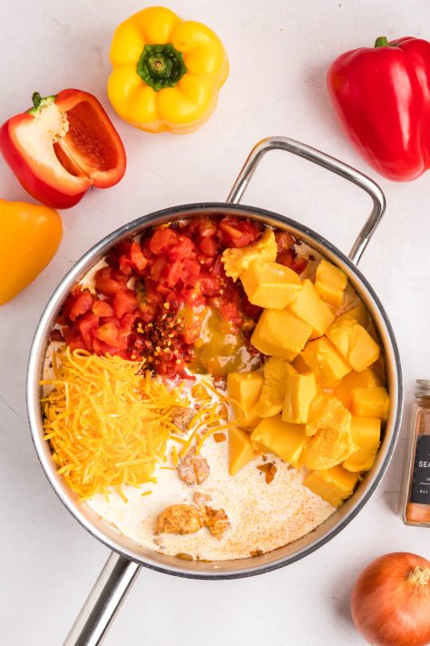 Velveeta, heavy cream, Rotel, cheddar cheese, Better Than Bouillon, and red pepper flakes being added to a skillet mixture.