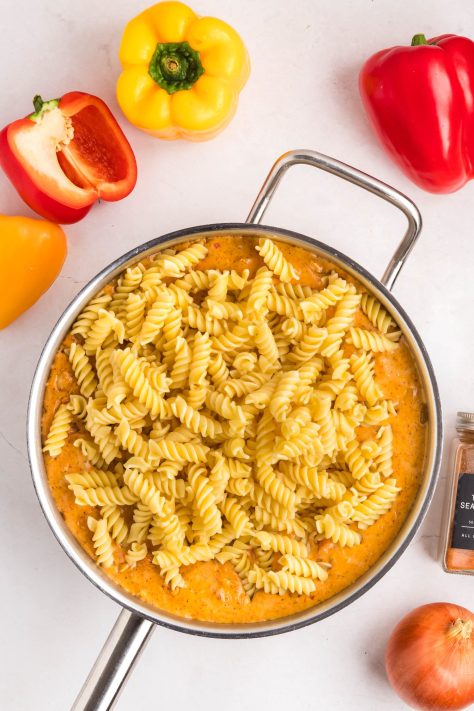 Pasta being added to a Cheesy chicken skillet.