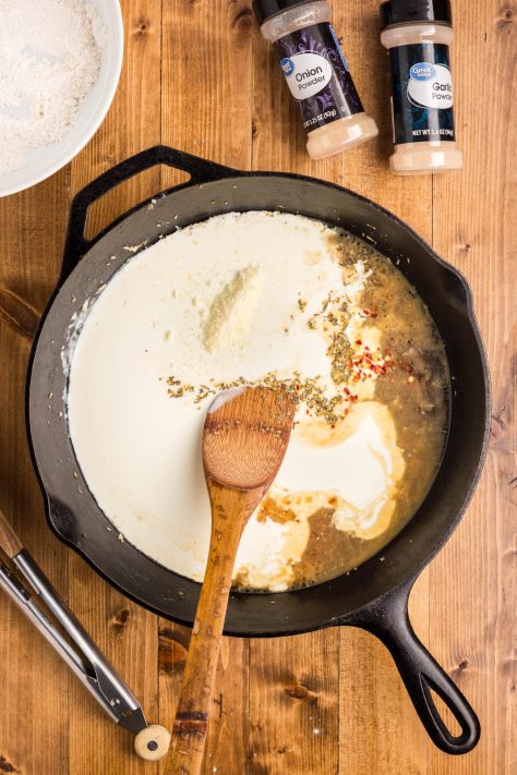 Heavy whipping cream and seasonings being added to a skillet.
