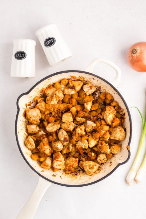 Onions, peppers, chicken and seasonings in a skillet.