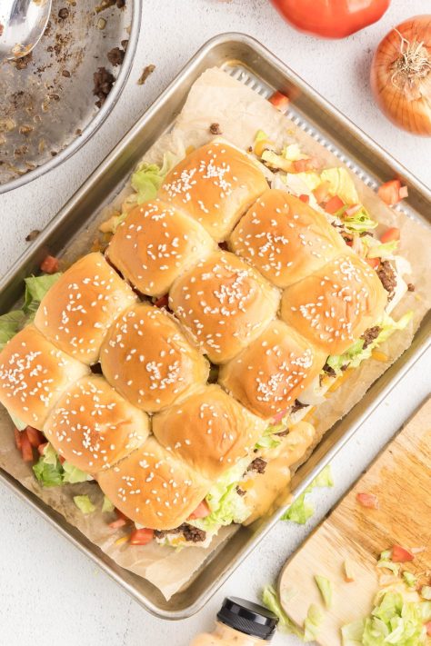 Slider buns with ground beef and cheese with toppings.
