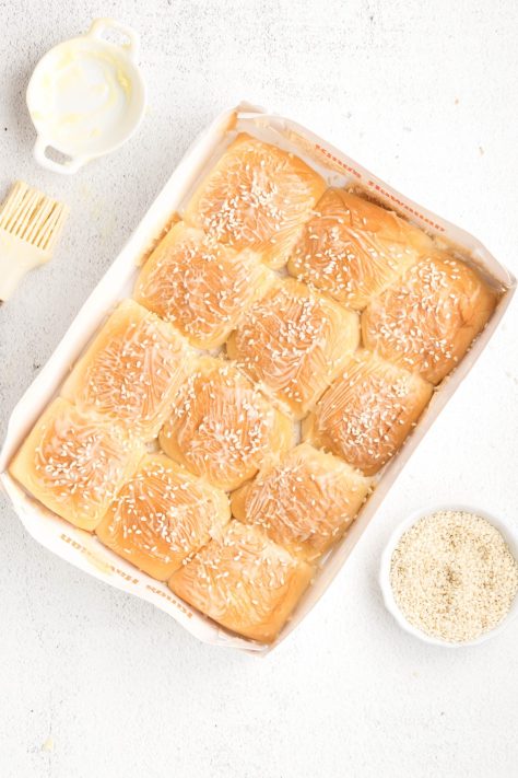 Slider bun tops with butter and sesame seeds on top.