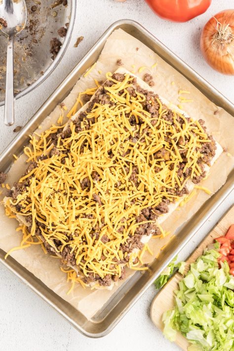Slider buns with ground beef and cheese on top.