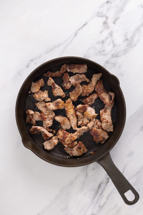 Steak cooking in a skillet.