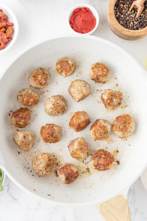 Meatballs cooking in a skillet.