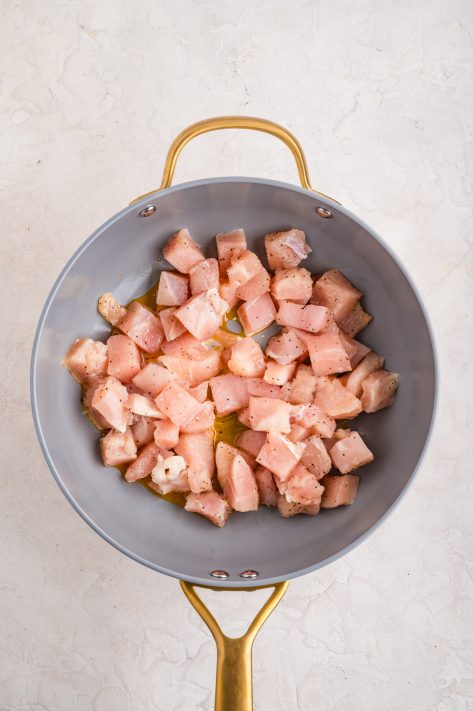 Chicken in a skillet cooking.