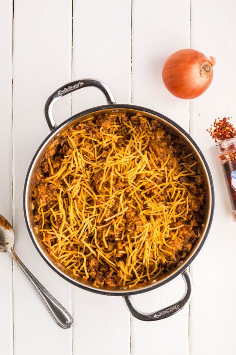 More cheese added to a Cheeseburger Rice dish in a pan.