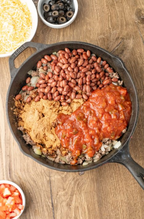 A skillet with beef, onions, taco seasoning, beans, and salsa.