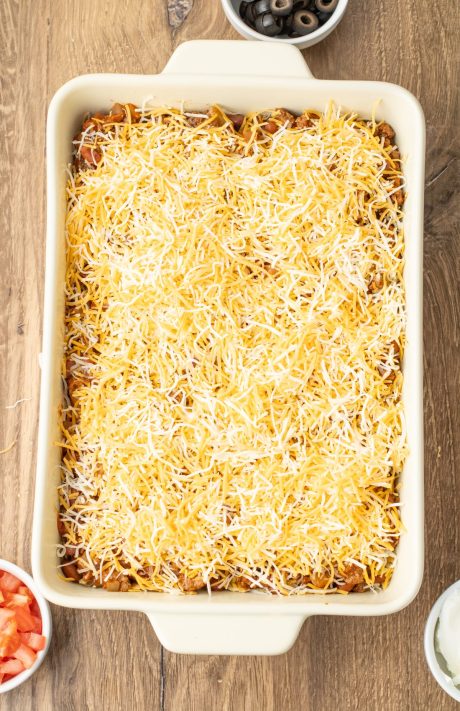 A baking dish with chips, layers of cheese, and beef.