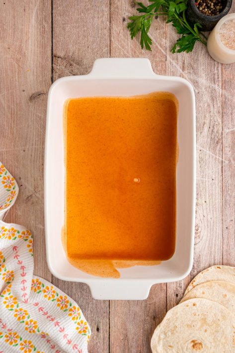 A layer of enchilada sauce in a dish.