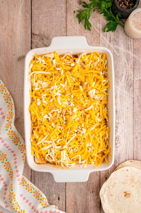 Filled tacos with enchilada sauce, and cheese in a dish.