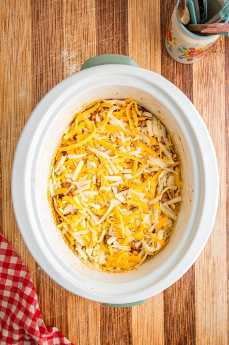 Shredded cheese on top of a chicken and rice mixture in a Slow Cooker.