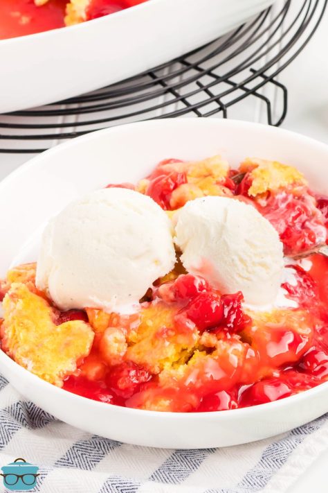 A serving bowl of 7 Up Cherry Dump Cake with two scoops of ice cream.