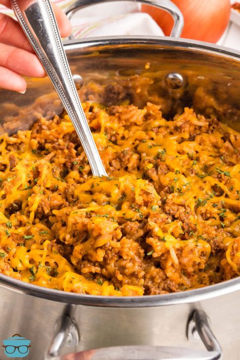 One Pan Cheeseburger Rice in a skillet being stirred up by a serving utensil.