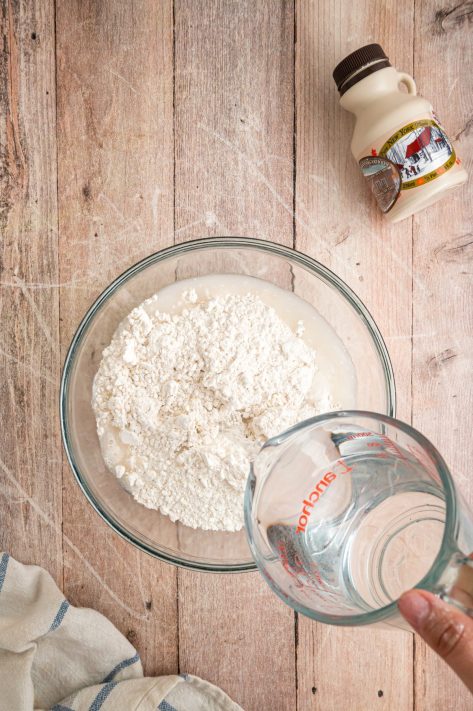 Water being added to pancake mix in a bowl.