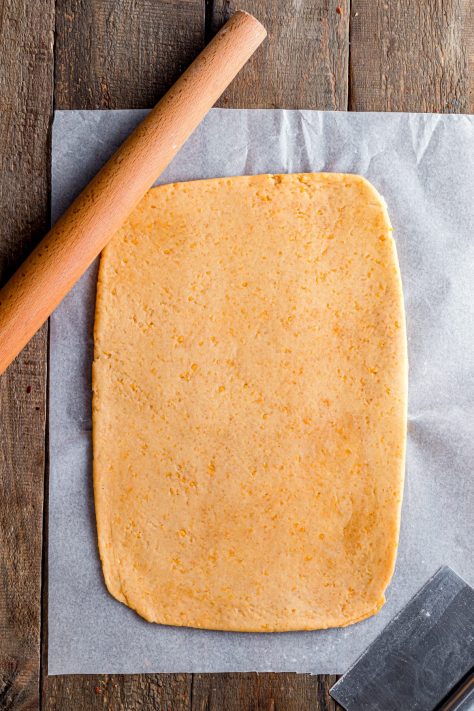 Cheese dough rolled out onto parchment paper.