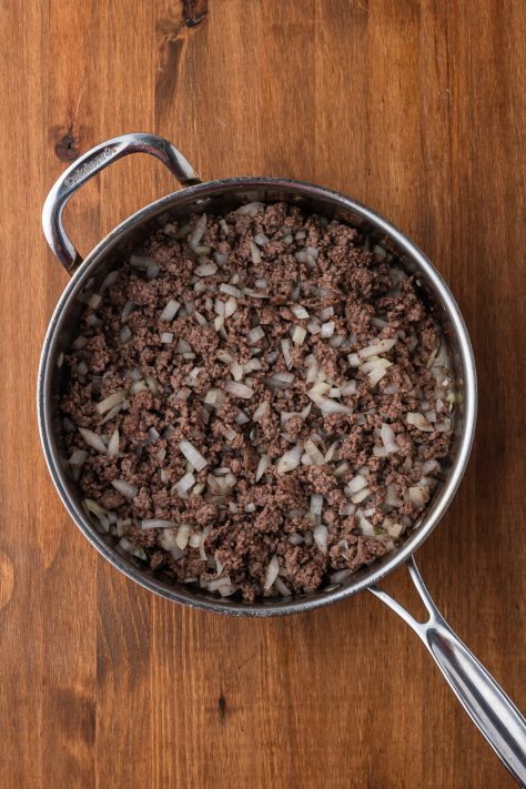 Ground beef and onion cooking in a skillet.