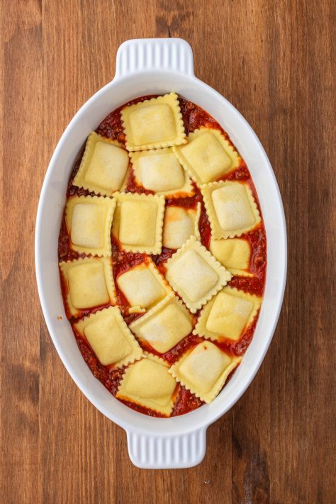 Ravioli in a baking dish on top of sauce.