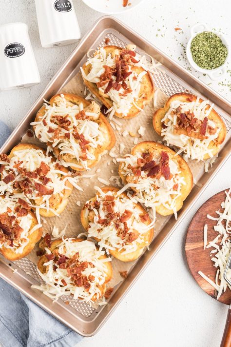 Pieces of Texas toast topped with chicken, Alfredo sauce, shredded cheese and bacon.