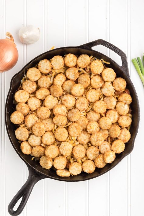 Crispy round tater tots on top of a ready to be baked casserole.