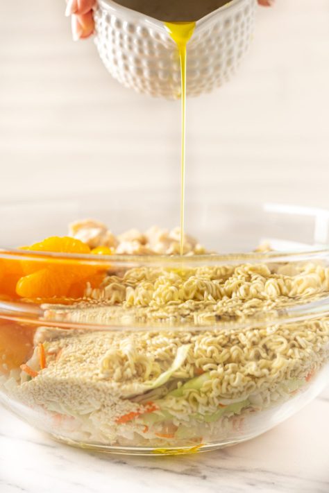 Dressing being poured over a chicken salad.