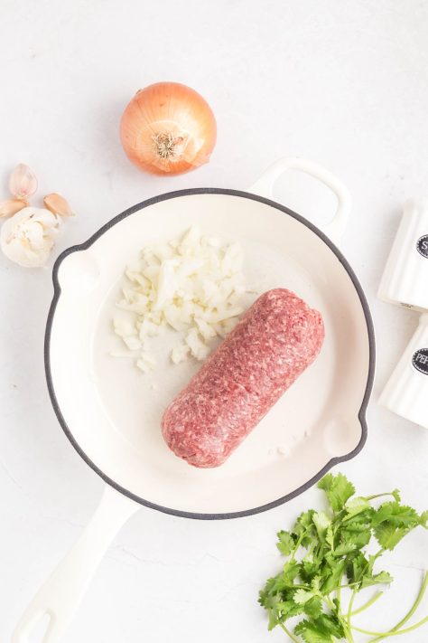 Ground beef and onion in a skillet.