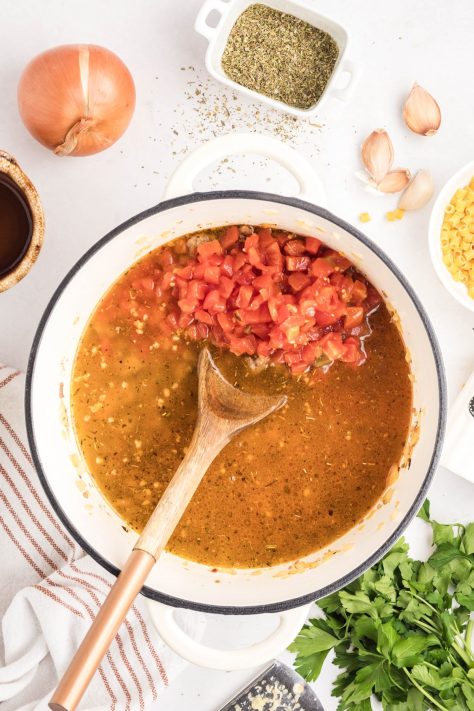 Broth and tomatoes being added to a beef and onion mixture.