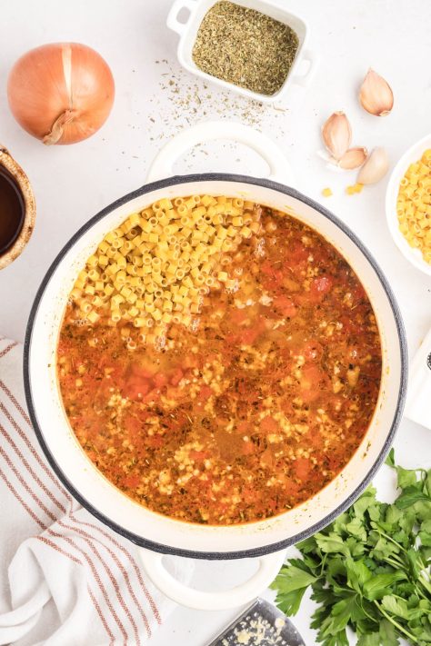Pasta being added to a pot of soup.
