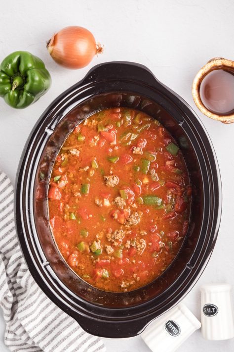A slow cooker with most of the ingredients for soup.