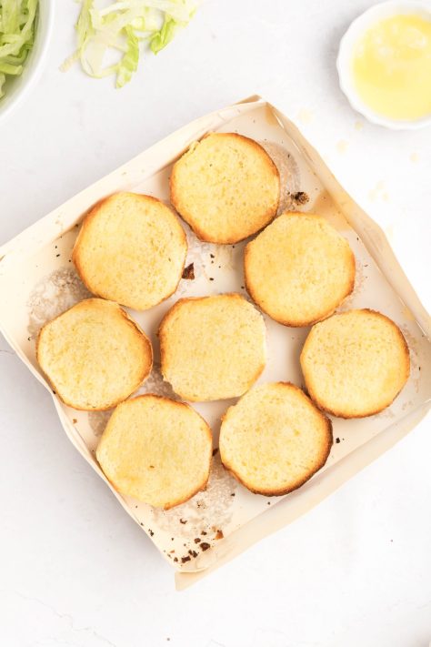 Toasted slider buns in a container.
