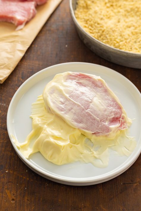 Pork chop in mayo on a plate.