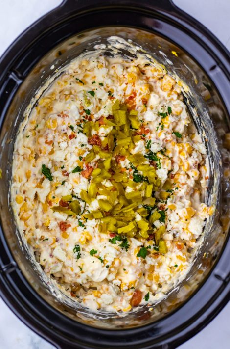 Jalalpenos and cheese being added to a Corn Dip in the Slow Cooker.