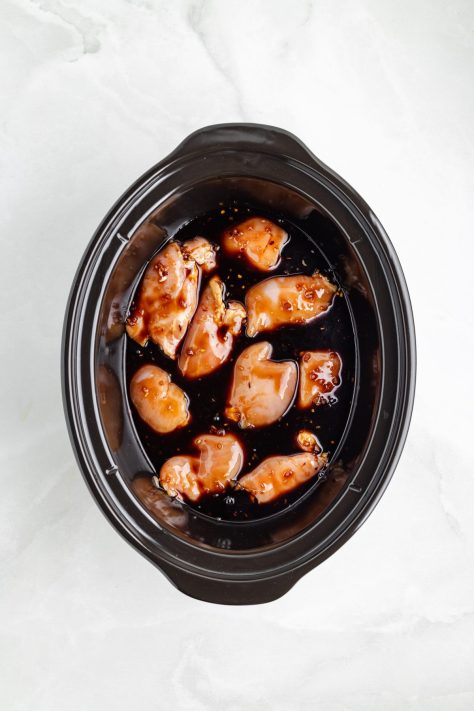 Sauce covered chicken thighs in a Slow Cooker.