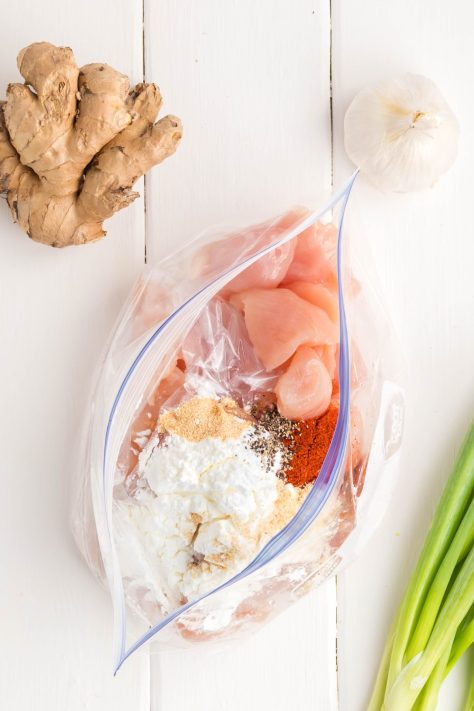 A bag with chicken, cornstarch, paprika, salt, pepper, garlic powder, and onion powder.
