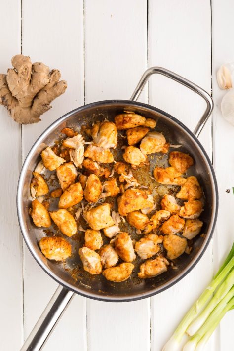 Coated chicken cooking in a skillet.
