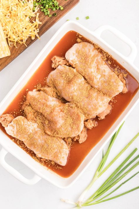 A baking dish with refried beans, taco seasoning, enchilada sauce and chicken.