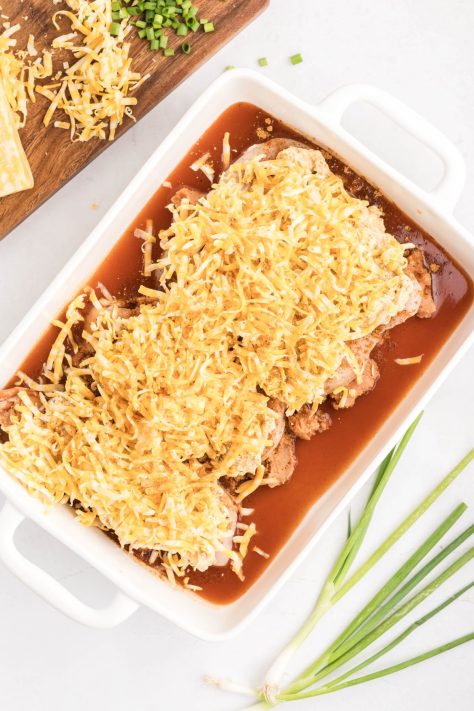 Shredded cheese on top of chicken, a cream cheese mixture, taco seasoning, refried beans and enchilada sauce.