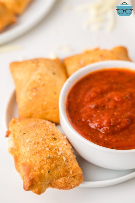 A few homemade Pizza Rolls and sauce in a bowl.
