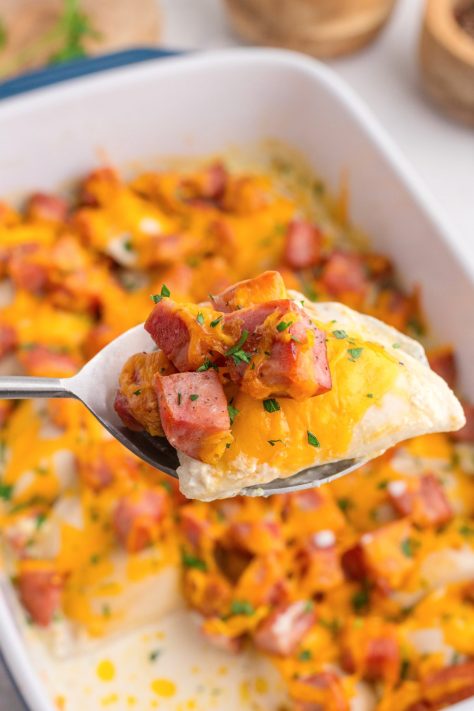 A spoon holding a bite of Pierogi and Kielbasa Casserole.