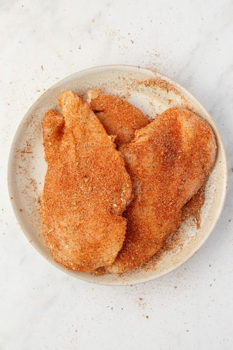 Seasoned chicken breasts on a plate.