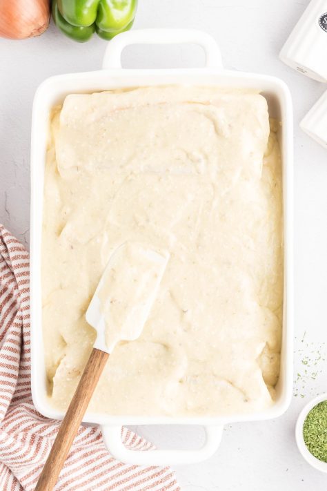 A baking dish with Beef Enchiladas topped with a creamy cheese sauce.