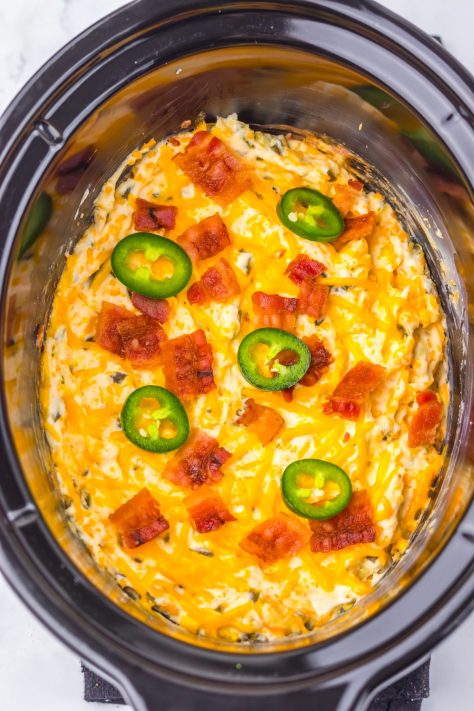 Jalapeno Popper Dip with bacon pieces and slices of jalapenos in a Slow Cooker.