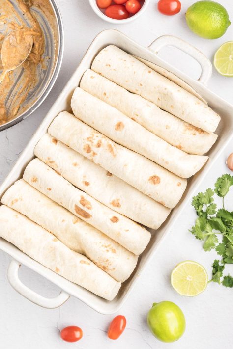 Enchilada filled tortillas rolled up and put in a baking dish.