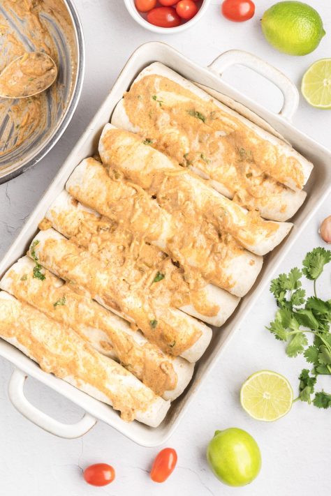 Enchilada sauce poured over tortillas with enchilada filling.