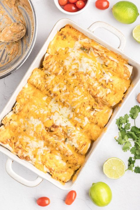 A bunch of baked Green Chicken Enchiladas in a baking dish.