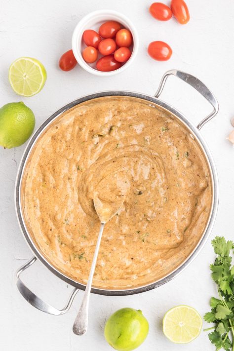 A skillet with garlic, enchilada sauce, sour cream, cilantro, green chiles, taco seasoning, and lime juice.