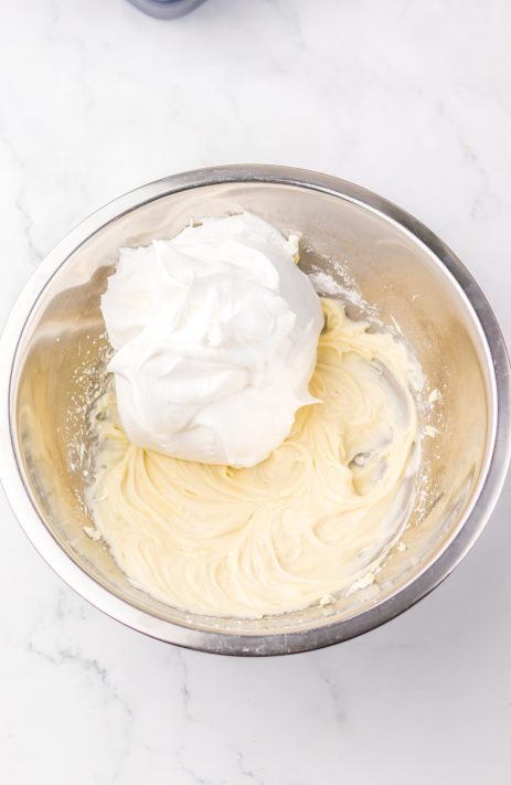 Whipped topping being beaten into a cream cheese frosting mixture.
