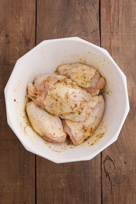 Chicken thighs being seasoned.