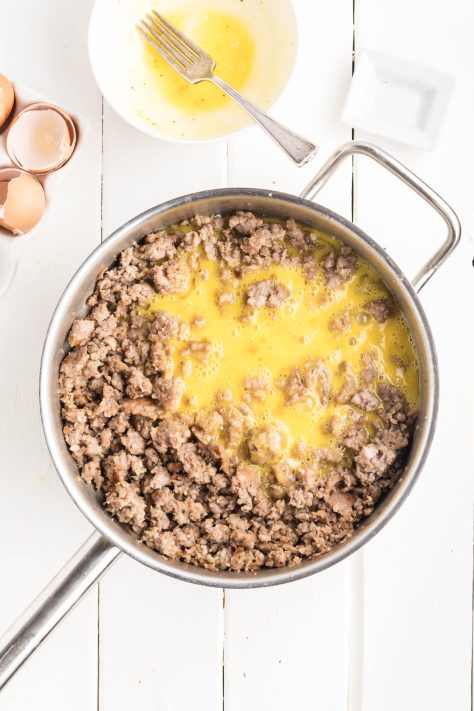 Sausage and raw eggs in a skillet.